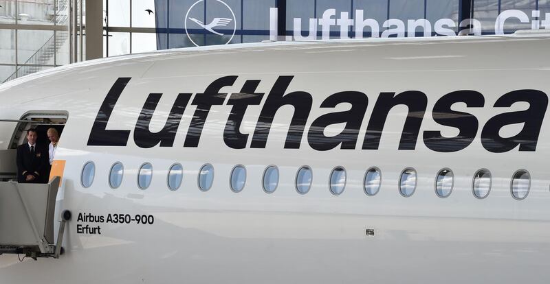 Lufthansa crew members stand at the door of the tenth Lufthansa Airbus A350-900 during the naming ceremony of the aircraft on July 30, 2018 at the Franz-Josef-Strauss airport in Munich, southern Germany. 
The aircraft bearing the registration D-AIXJ was named after the town of Erfurt. / AFP PHOTO / Christof STACHE