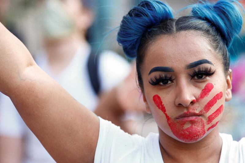 A woman with a red hand painted on her face, which calls attention to the high rates of indigenous women who are murdered or missing, raises a sign in solidarity in Denver, Colorado. Reuters