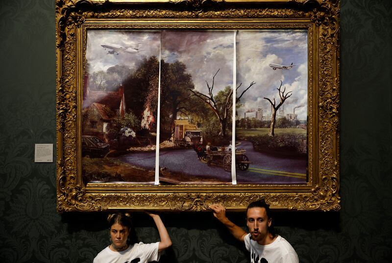 Activists glue their hands to the frame of the painting 'The Hay Wain' on July 4. AFP
