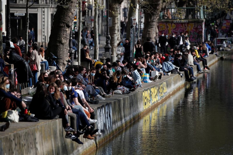 People sit along the Canal Saint-Martin in Paris, France, as the country enters its third lockdown. Reuters