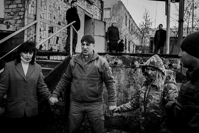 Oleg Tkachenko, 47, a chaplin from the Good News Church in Slavyansk, prays with soldiers and volunteers at a meeting in the front-line town of Mariinka. Photo by Alex Masi.