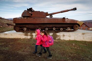 Kosovan-Albanian children walk near by a destroyed Serbian military tank in the village of Fushtica in Kosovo. EPA
