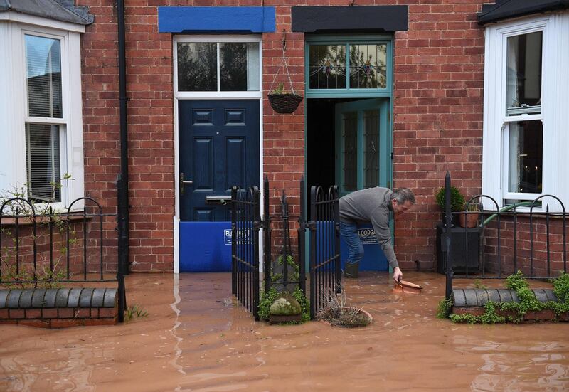 A man rescues a floating plant pot from flood water, outside of a flood-bound house in Tenbury Wells, after the River Teme burst its banks in western England.  AFP