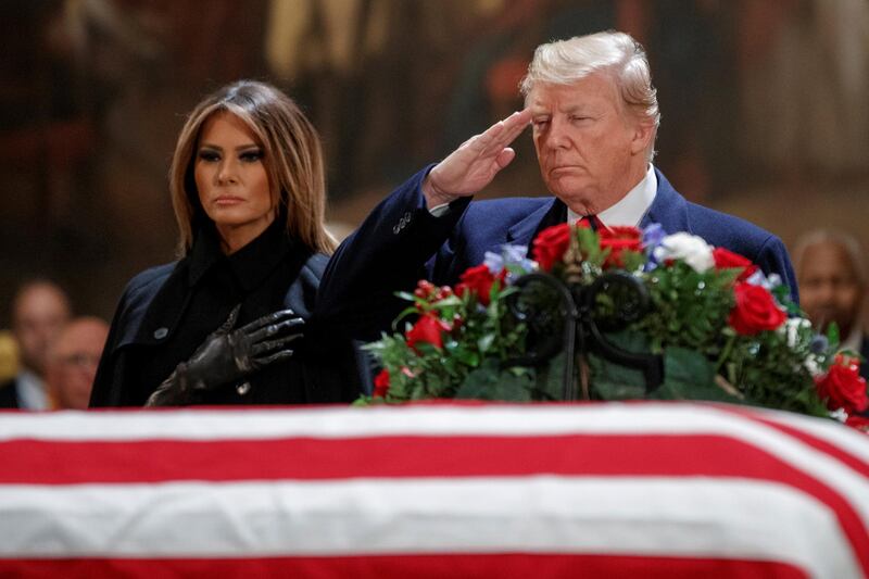 Donald Trump, with First Lady Melania Trump, salutes the casket containing the body of former US President George HW Bush in the Rotunda of the US Capitol in Washington. Reuters