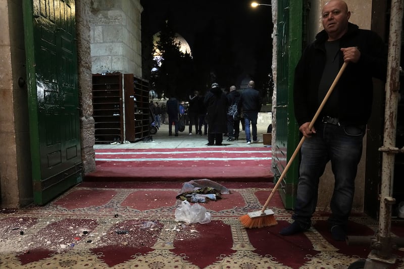 A worshipper sweeps the debris in the aftermath of the attack by Israeli police. AP
