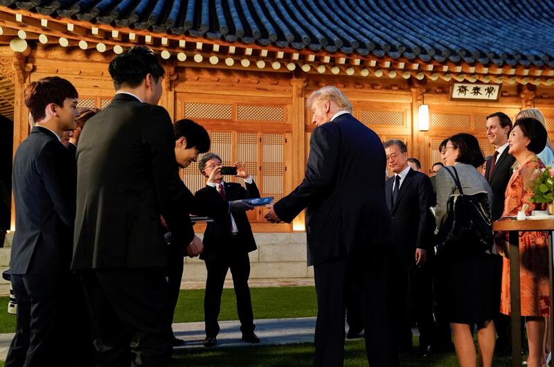 US President Donald Trump receives a copy of an album from members of the K-pop boy band Exo as he arrives for dinner at the Blue House in Seoul. Reuters