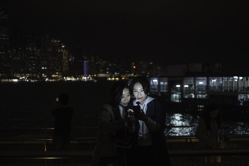 Two women look at a mobile phone after the skyline buildings lights were switched off for the Earth Hour environmental campaign in Hong Kong. Philip Fong / AFP