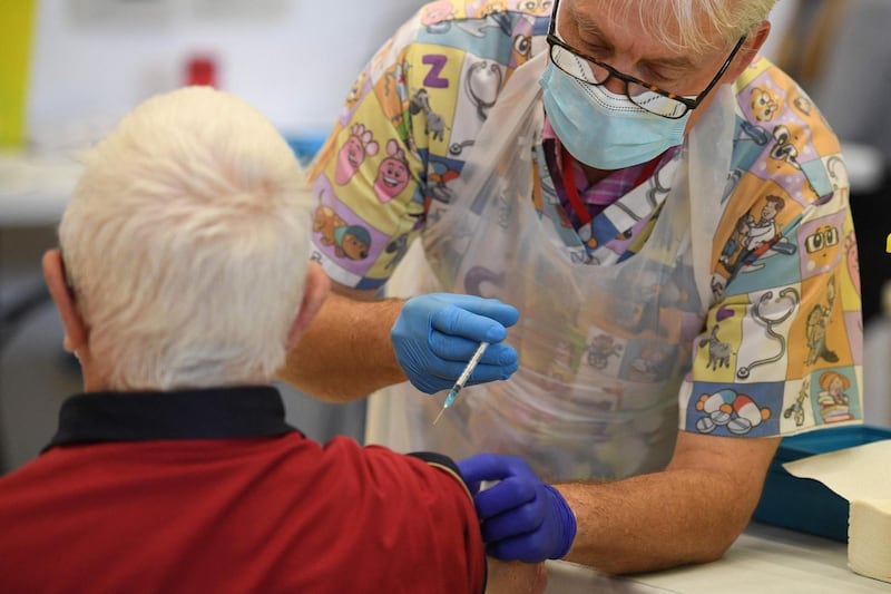 A health worker administers a dose of the BioNTech/Pfizer covid-19 vaccine at a vaccination clinic set up inside the Derby Arena at Pride Park in Derby, Derbyshire on March 31, 2021. On March 28, 2021, Britain passed the milestone of giving the first vaccine dose to more than 30 million adults, and the government plans to allow outdoor drinking in pub gardens and non-essential retail such as hairdressers in England from April 12. / AFP / Oli SCARFF
