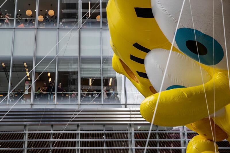 People watch from an office as a SpongeBob SquarePants balloon moves through Sixth Avenue during the Macy's Thanksgiving Day Parade in New York. AP