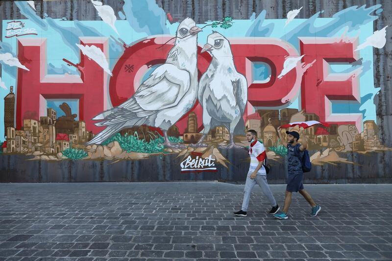 People walk past a "Hope" graffiti painted on a fenced off entrance of a hotel that was damaged by the August 4 seaport blast on the first anniversary of anti-government protests. Getty Images