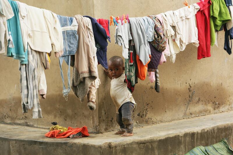 A toddler plays near a laundry line filled with clothes at a farm on the outskirts of Harare, Zimbabwe. AP