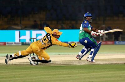 Zeeshan Ashraf of Multan Sultans who scores 50 off 35 balls, cuts a boundary as Peshawar Zalimi's Kamran Akmal looks on during the Pakistan Super League match at the National Stadium in Karachi, Pakistan, Friday, March 13, 2020. (AP Photo/Fareed Khan)