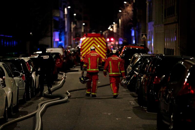 Firefighters and a police officer are seen near a building that caught fire in the 16th arrondissement in Paris, on February 5, 2019.  Seven people died and another was seriously injured in a building fire in a wealthy Paris neighbourhood on Monday night, the fire service said. The blaze, which took hold in an eight-storey block in the French capital's trendy 16th arrondissement, left 24 people, including two firefighters, with minor injuries.
 / AFP / Geoffroy VAN DER HASSELT

