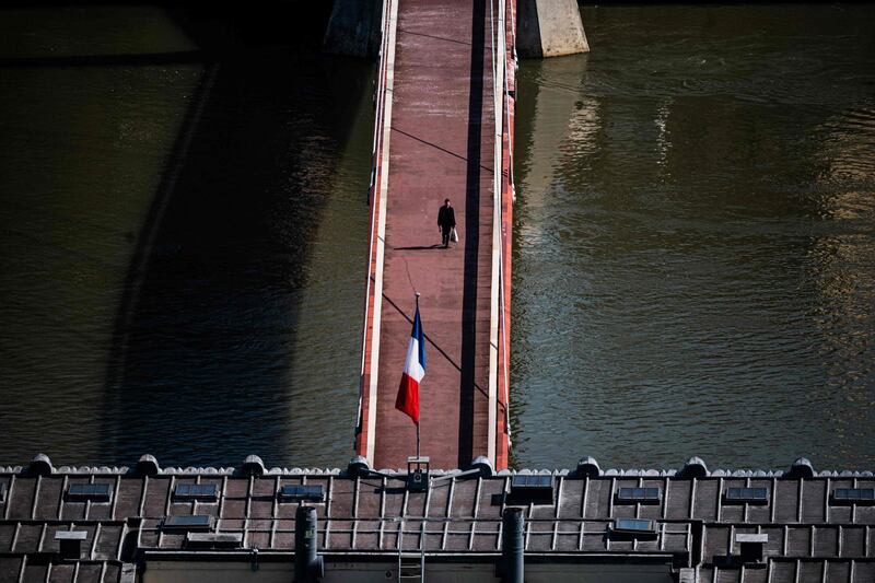 A person walks on the deserted Passerelle du Palais de Justice in Lyon, central eastern France as a strict lockdown comes into in effect.  AFP