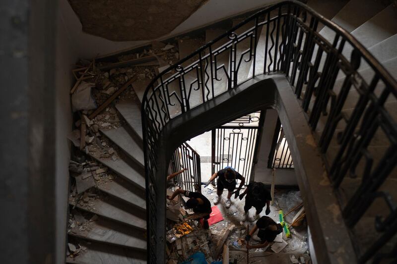 People remove debris of a damaged building at a neighborhood near the scene of Tuesday's explosion that hit the seaport of Beirut, Lebanon, Friday, Aug. 7, 2020.  Rescue teams were still searching the rubble of Beirut's port for bodies on Friday, nearly three days after a massive explosion sent a wave of destruction through Lebanon's capital. (AP Photo/Felipe Dana)