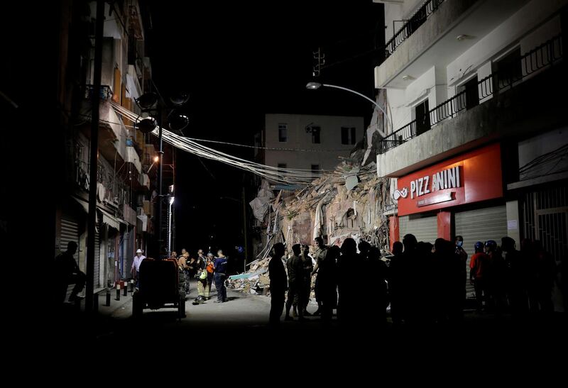 Onlookers gather as rescue workers dig through the rubble of a badly damaged building in  Lebanon's capital Beirut in search of possible survivors from a mega-blast at the adjacent port one month ago. AFP