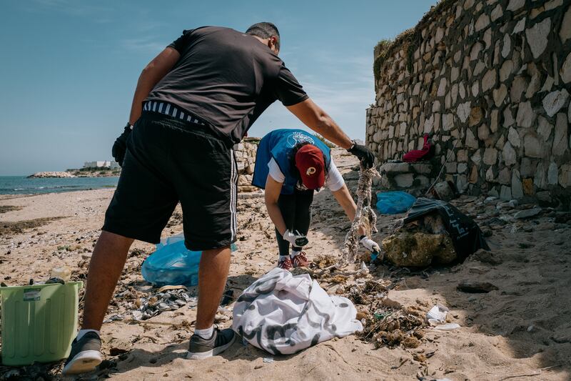 Volunteers with Tounes Clean-up and Oceanis, two environmental NGOs based in Tunisia, sift through the sand at a beach north of Tunis.