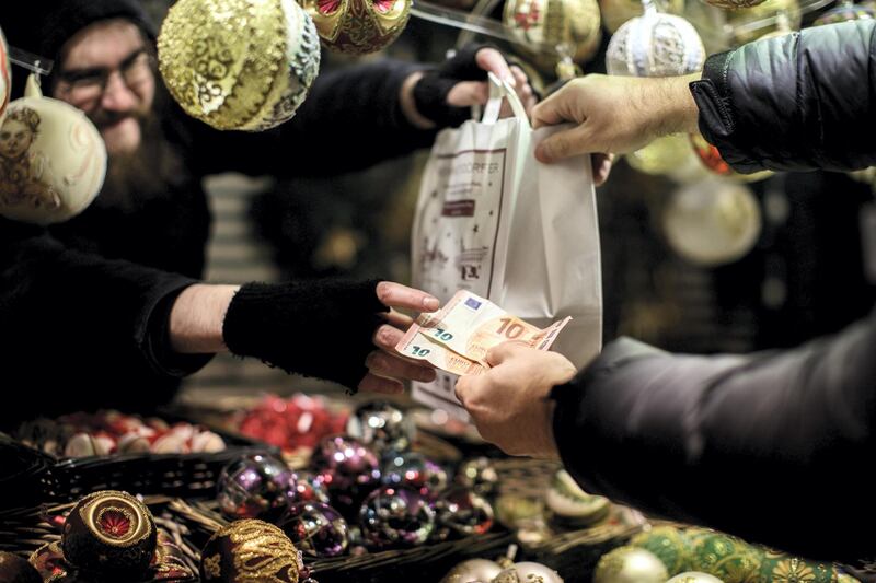 A Shopper hands a stall holder two ten euro currency bank notes at a festive market on Maria-Theresien-Platz square in Vienna, Austria, on Thursday, Dec. 8, 2016. The Viennese Christmas market in front of City Hall runs from Nov. 12 to Dec. 24. Photographer: Lisi Niesner/Bloomberg