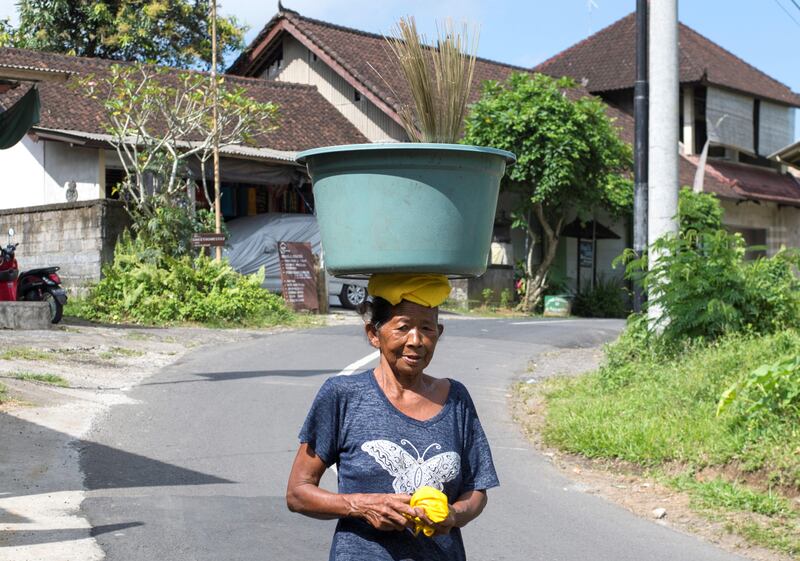 A Balinese woman carries a bucket on her head, where many villagers left for shelters due to Mount Agung volcanic activities, in Karangasem on Bali island on September 29, 2017. 
A rumbling volcano on the holiday island of Bali is spewing steam and sulphurous fumes with more intensity, heightening fears of an eruption as officials said the number of evacuees had topped 144,000. / AFP PHOTO / BAY ISMOYO