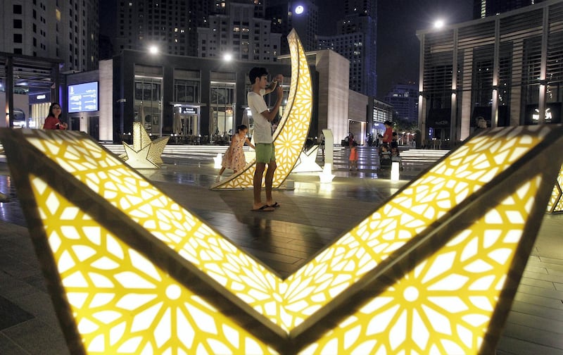 Dubai, United Arab Emirates - July 9, 2015.  Kids and adults find time to go around on the a public art installation al JBR's The Walk. FOLLOWING TEXT FROM PRESS RELEASE: The Walk at JBR, in collaboration with leading artists, artisans and chefs of the UAE, will host for the first time a unique concept in celebration of Ramadan. RWAQ Ramadan is a month-long event focused on bringing to life the region’s rich heritage, connecting residents and tourists to the spirit of the Holy Month through an exceptional experience. Tahir Sultan and Loop.pH, have been commissioned to design a unique visual interpretation of Ramadan. The first installation, titled “1001 Nights, Alf Laila wa Laila”, is a full-scale light installation of larger-than-life 3D stars.  ( Jeffrey E Biteng / The National )  Editor's Note; Standalone *** Local Caption ***  JB090715-Standalone03.jpg