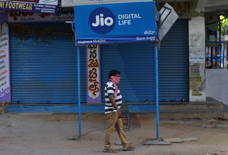 A man walks past a Reliance Jio signage in front of a closed shop in Hyderabad, India, Wednesday, April 22, 2020. Facebook says it plans to invest $5.7 billion in Indiaâ€™s telecom giant Reliance Jio. The investment will give Facebook a 9.99% stake in Jio Platforms, the digital technologies and app developing division of Reliance Industries. (AP Photo/Mahesh Kumar A.)