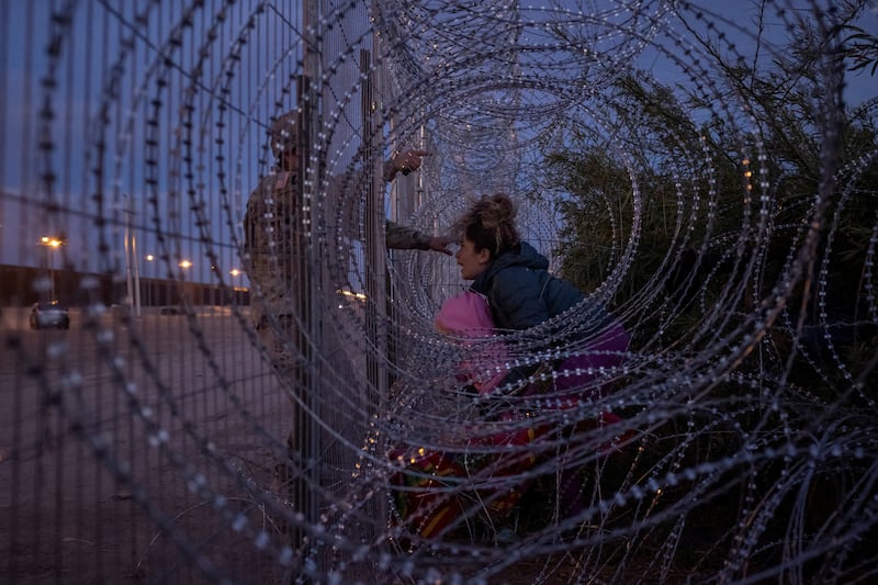 Eliana, 22, a migrant from Venezuela, holds her three-year-old daughter Chrismarlees as she shouts at National Guard soldier after he stopped her from breaching a razor wire-laden fence along the bank of the Rio Grande river in El Paso, Texas. Reuters