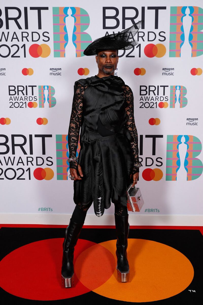 Billy Porter poses on the Brits red carpet in a black lace dress with matching hat. Reuters