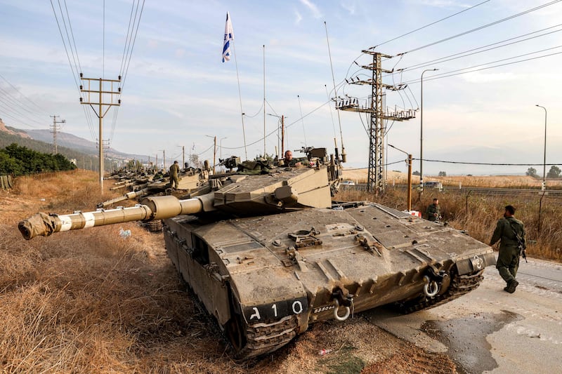 An Israeli army soldier passes a Merkava battle tank in northern Israel near the border with Lebanon. AFP