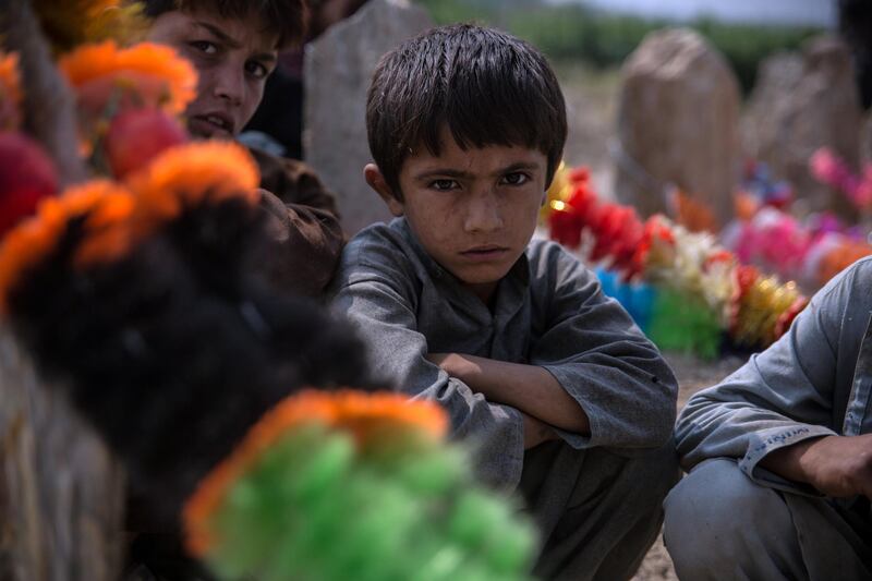 Lal Agha, 8, sits by the grave of his father Khyber, 25, who was killed in a US drone strke last week. 