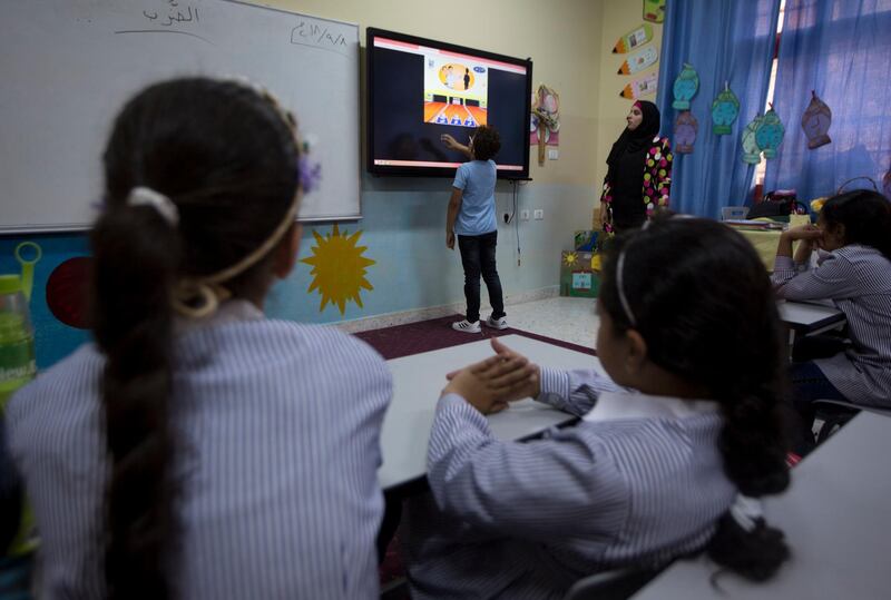A  Palestinian child uses a large touch screen during a class at the Ziad Abu Ein School in Ramallah, West Bank. AP