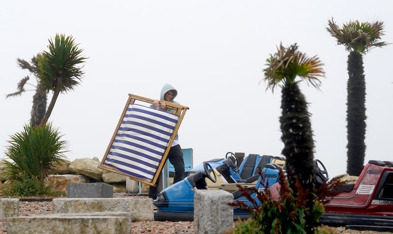 A deckchair attendant battles the wind on the deserted beach at Folkestone in Kent