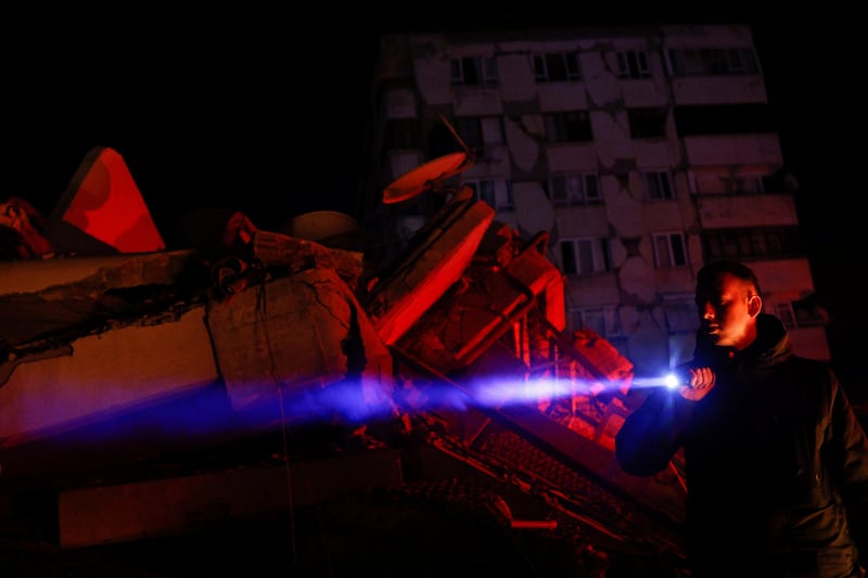 A man uses a lantern to check damaged buildings. Reuters