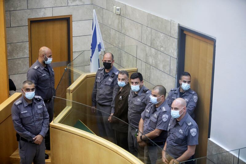 Re-arrested Palestinian escapee Yakub Kadari is surrounded by guards in a courtroom in Nazareth. Six Palestinians broke out of a prison in northern Israel through a tunnel, triggering a manhunt. Four have been captured. AP