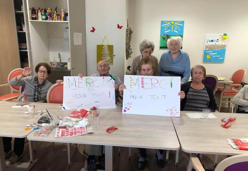 In this photo provided by the Vilanova nursing home, residents show posters reading "Thank you for everything" on April 27 2020 in Corbas, central France. The nursing staff of the care home in Lyon decided 45 days ago that rather than lock residents in their rooms as the government urged, the staff would lock themselves in the home with residents so as not to deprive the elderly of their freedom. The home has had zero virus cases so far. (Valerie Martin via AP)