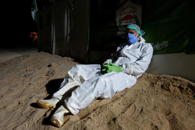 Abdelhussan Kadhim, from the PMF, who volunteered to work in the cemetery, wearing a protective suit, takes a rest at the new Wadi Al Salam cemetery, which is dedicated to those who died of the coronavirus disease. REUTERS