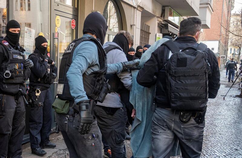 A man is led away by police with a blanket over his head during a raid in Berlin, Germany, Thursday, Feb. 18, 2021. Police cracked down on clan crime in Berlin and the surrounding area with a major raid on Thursday morning. (Christophe Gateau/dpa via AP)