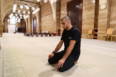 Muhammad Mokaev prays at Al Fateh Grand Mosque in Manama, Bahrain. The UFC fighter is a devout Muslim and his faith is a driving force in both his career and life. Chris Whiteoak / The National