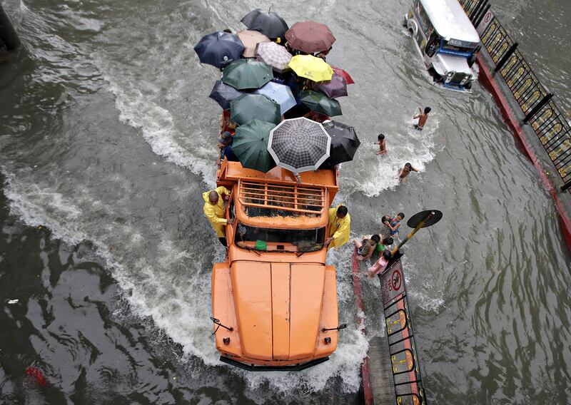 A truckload of stranded commuters cross a flooded street in Manila, Philippines Monday, Aug. 19, 2013. Torrential rains brought the Philippine capital to a standstill Monday, submerging some areas in waist-deep floodwaters and making streets impassable to vehicles while thousands of people across coastal and mountainous northern regions fled to emergency shelters. (AP Photo/Aaron Favila)