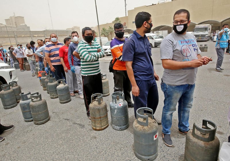 Paople queue in front of a shop to refill their gas cylinders in Kuwait City on May 10, 2020, a day after Kuwaiti authorities announced a 20-day total lockdown due to the COVID-19 pandemic. The lockdown will be implemented from May 10 to 30, during which public sector tasks will be performed remotely while private sector activities are suspended except for essential functions, Kuwait's relevant authorities announced on Twitter. / AFP / YASSER AL-ZAYYAT
