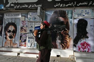 A Taliban fighter passes a beauty salon in Kabala with images of women defaced using spray paint. AFP