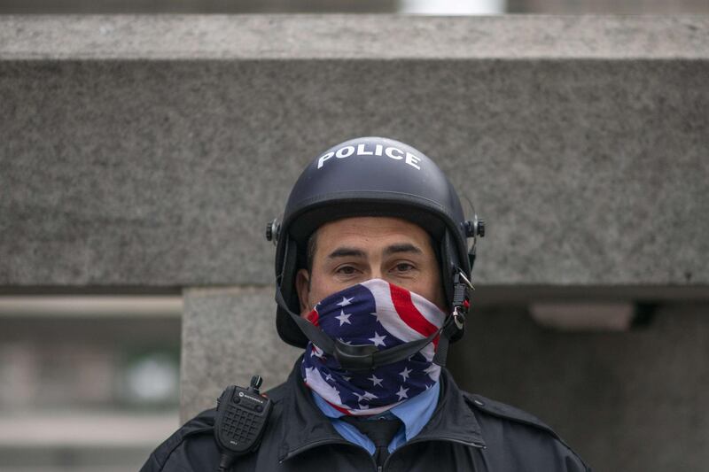 PHILADELPHIA, PA - OCTOBER 30: A Police officer wearing a patriotic gaiter due to the coronavirus pandemic gathers near Philadelphia City Hall with members of the National Guard on October 30, 2020 in Philadelphia, Pennsylvania. In response to widespread unrest in the aftermath of Walter Wallace Jr.'s death, the National Guard arrived this afternoon to various locations throughout the city. The 27-year-old Walter Wallace Jr, a father of nine children, who Philadelphia police officers claimed was armed with a knife, was fatally shot by at least 14 total rounds.   Mark Makela/Getty Images/AFP
== FOR NEWSPAPERS, INTERNET, TELCOS & TELEVISION USE ONLY ==
