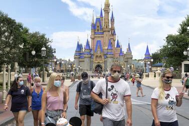 Guests wear masks at the official reopening day of the Magic Kingdom at Walt Disney World in Florida last month. A $1bn resort technology project is one of the the investments that has been cut as Walt Disney focuses on its Disney+ streaming platform. AP Photo 
