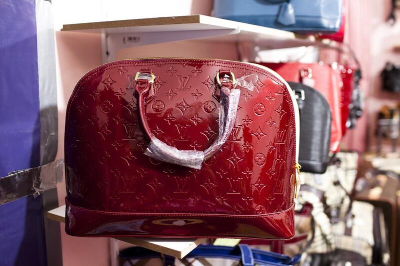 Counterfeit handbags designed by Louis Vuitton and Chanel sit on shelves of a secret room of a store at Karama Market in Dubai. Andrew Henderson / The National

