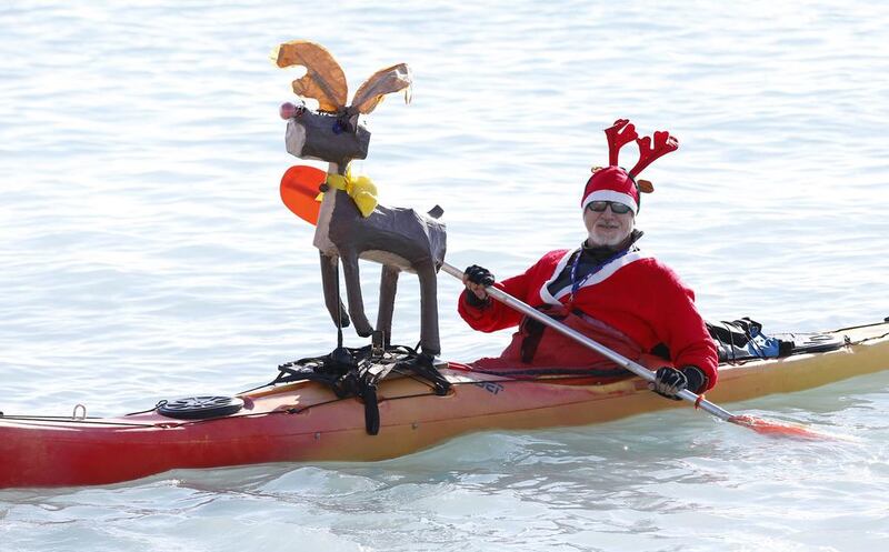 A man wearing a Santa Claus outfit paddles his canoe decorated with a reindeer in papier-mache during the traditional Christmas bath on December 21 on the beach in downtown Nice. Valery Hache/ AFP