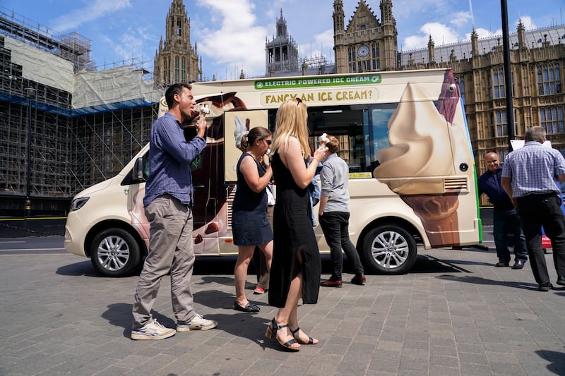 People eat ice cream outside the houses of Parliament in London. AP 