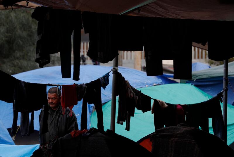 A man walks between tents and hanging laundry at a sports complex sheltering thousands of Central Americans. AP Photo