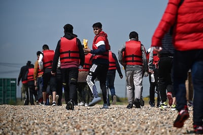 Migrants walk up the beach in Dungeness, on the south-east coast of England, after being picked up at sea by the Royal National Lifeboat Institution while attempting to cross the English Channel, in June. AFP