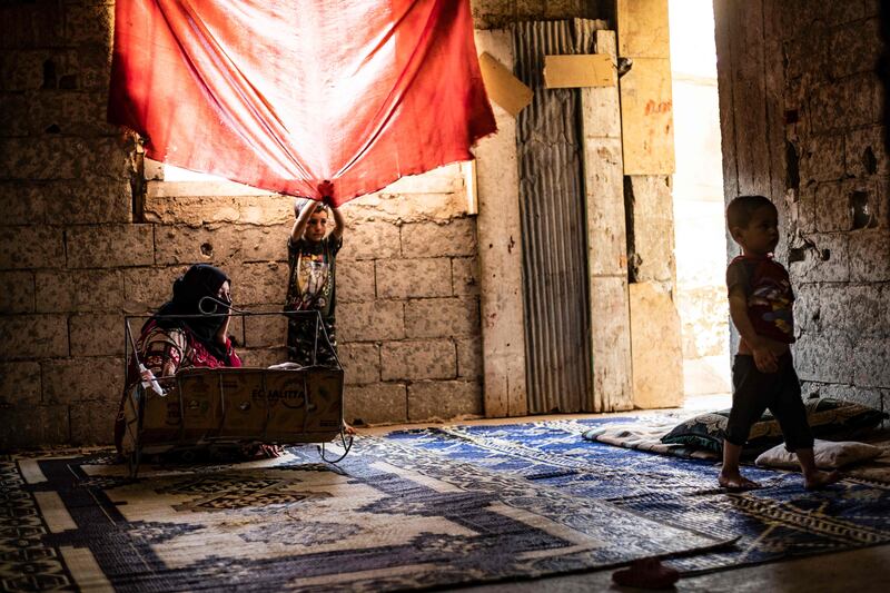 A Syrian mother, displaced with her family from Deir Ezzor, rocks a baby to sleep inside the damaged building where she is living in Syria's northern city of Raqqa.