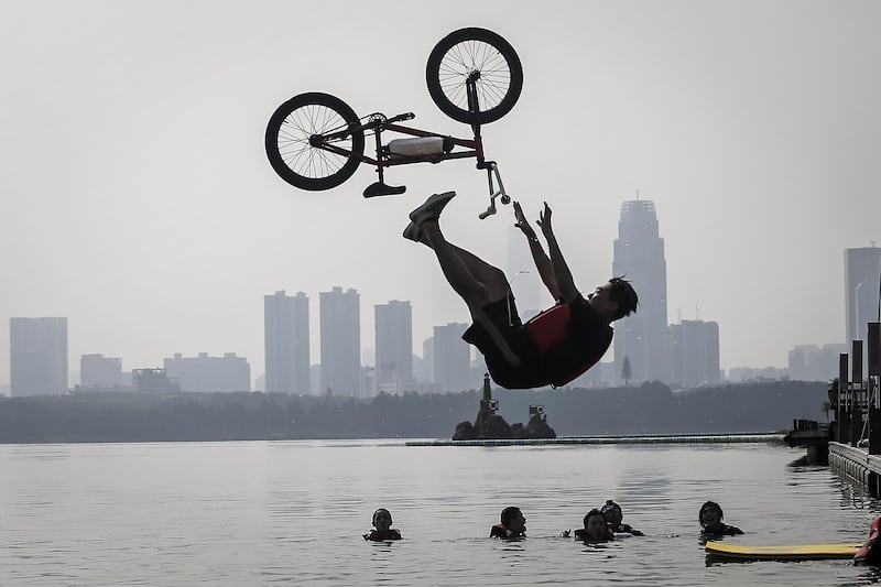An extreme cycling enthusiast performs a stunt before falling into the East Lake in Wuhan, China on August 22. Getty