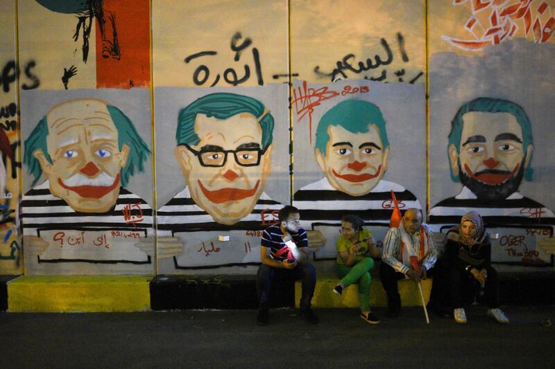 November 17, 2019 - Beirut, Lebanon: Thousands of protesters gather on Martyrs' Square to celebrate one month since the beginning of the Lebanese revolution. These protesters take a break and sit down in front of a wall that has been covered by caricature of Lebanon's politicians, including Walid Joumblatt, Michel Aoun, Gebran Bassil, and Saad Hariri.
Des milliers de manifestants celebrent un mois de soulevement populaire sur la Place des Martyrs.

NO USE FRANCE